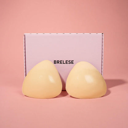 Beige Double Sticky Push-up bra inserts are showcased from the back, next to a pink Brelese box in front of a pink background.